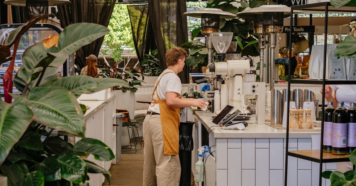 Barista připravuje kávu za pultem v moderní kavárně.