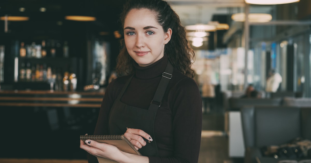 Žena v zástěře s tabletem v restauraci.